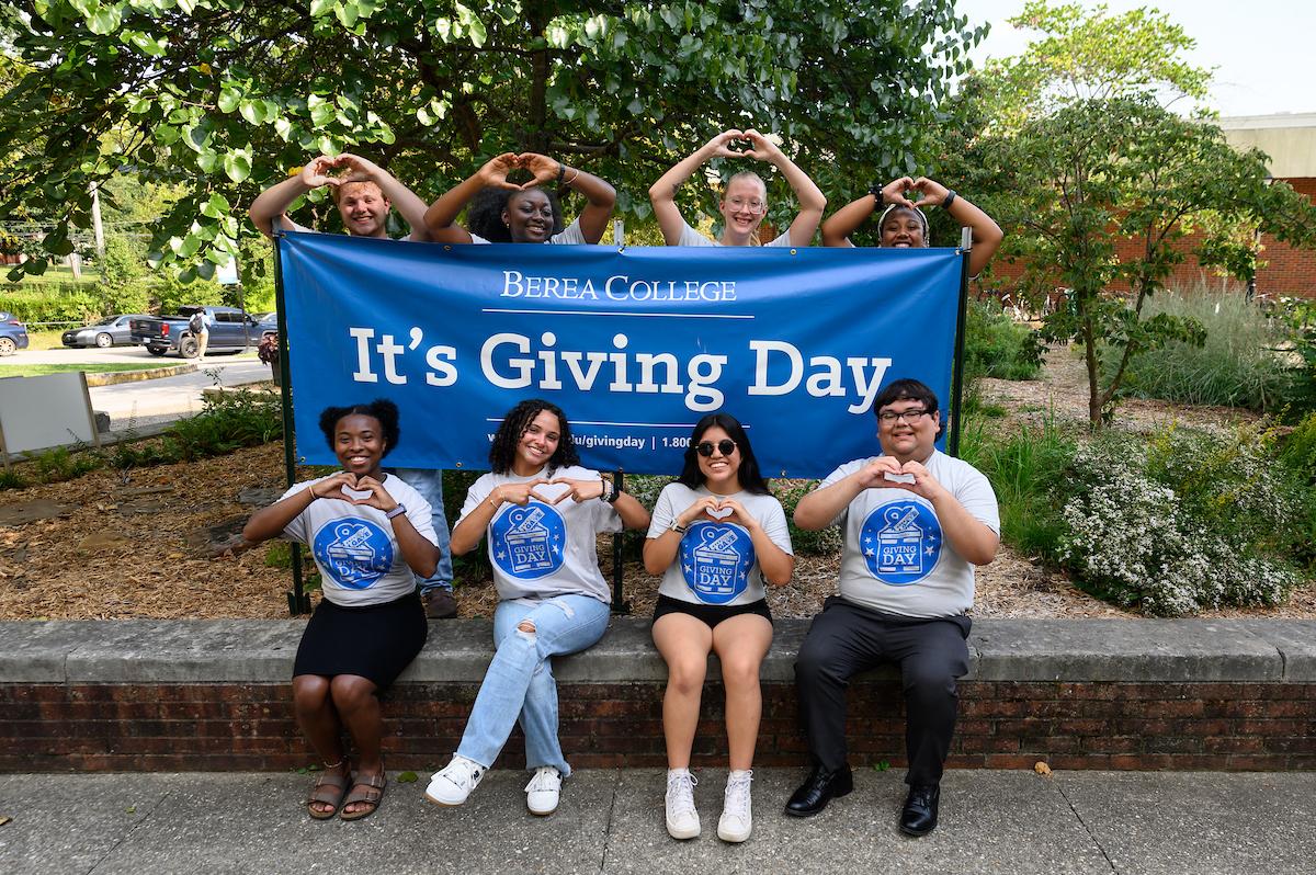 Berea College students behind a Giving Day sign in front of the Alumni Building.